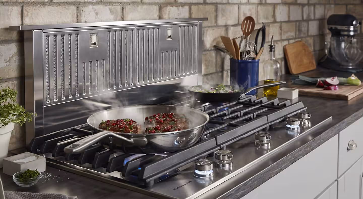 Food cooking in front of a retractable downdraft vent