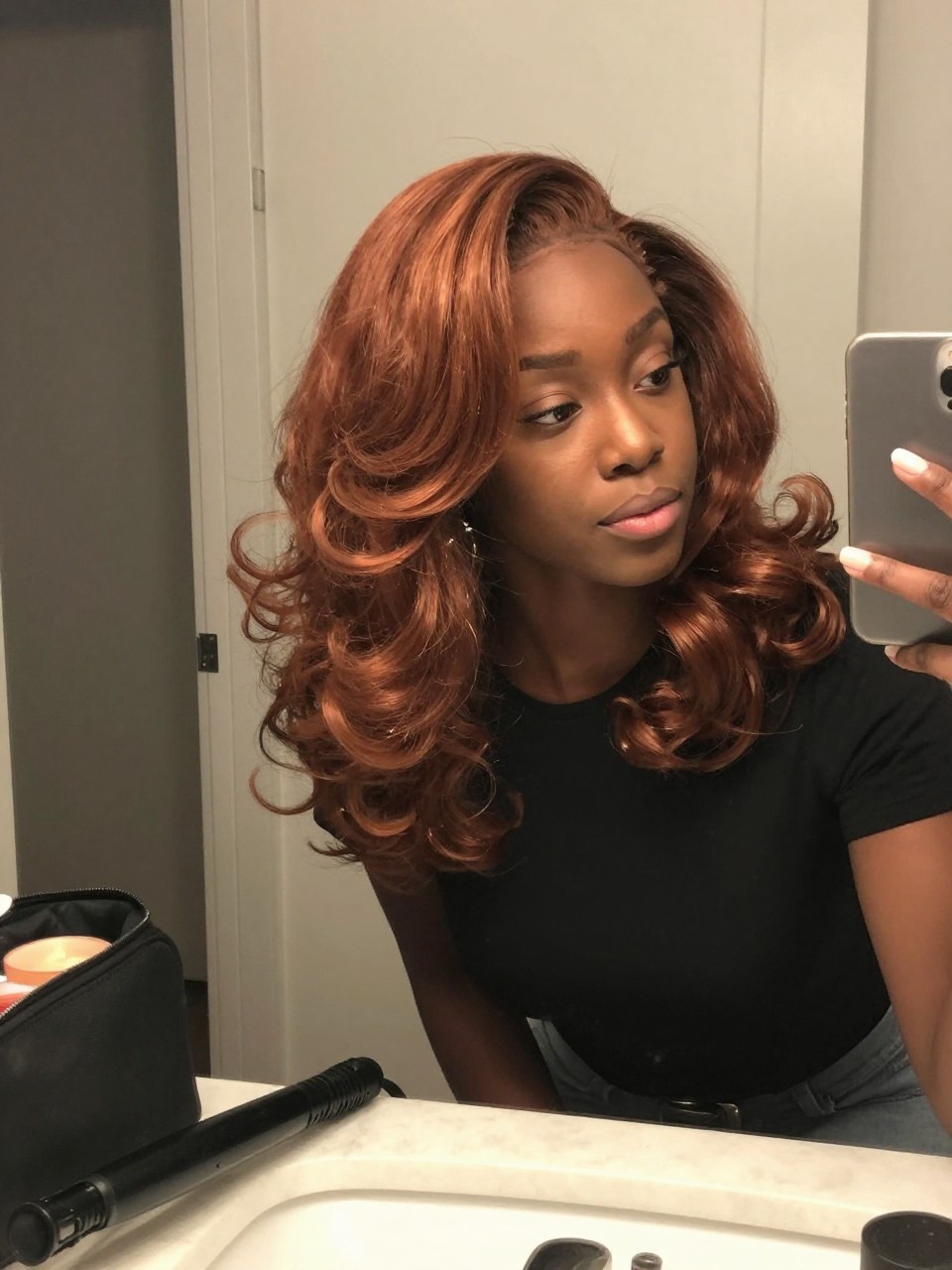 Image de référence : Photo d’une femme noire portant des boucles cuivrées mi-longues avec une raie profonde sur le côté, des pointes brillantes et incurvées, et un volume important sur le côté, selfie pris sur le vif devant un miroir légèrement de côté, dans une salle de bain avec un miroir de coiffeuse, sous un éclairage intérieur doux, le fer à boucler refroidissant sur le comptoir à côté d’une trousse de maquillage, une boucle d’oreille remarquable visible à travers les boucles, un moment réaliste de préparation pour un dîner d’automne, qualité photo du dernier iPhone.